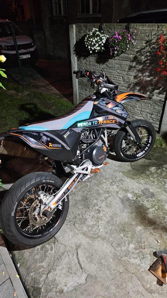 Motorcycle parked on a stone surface with a building and plants in the background
