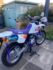 Yamaha dirt bike on a stand in front of a shed