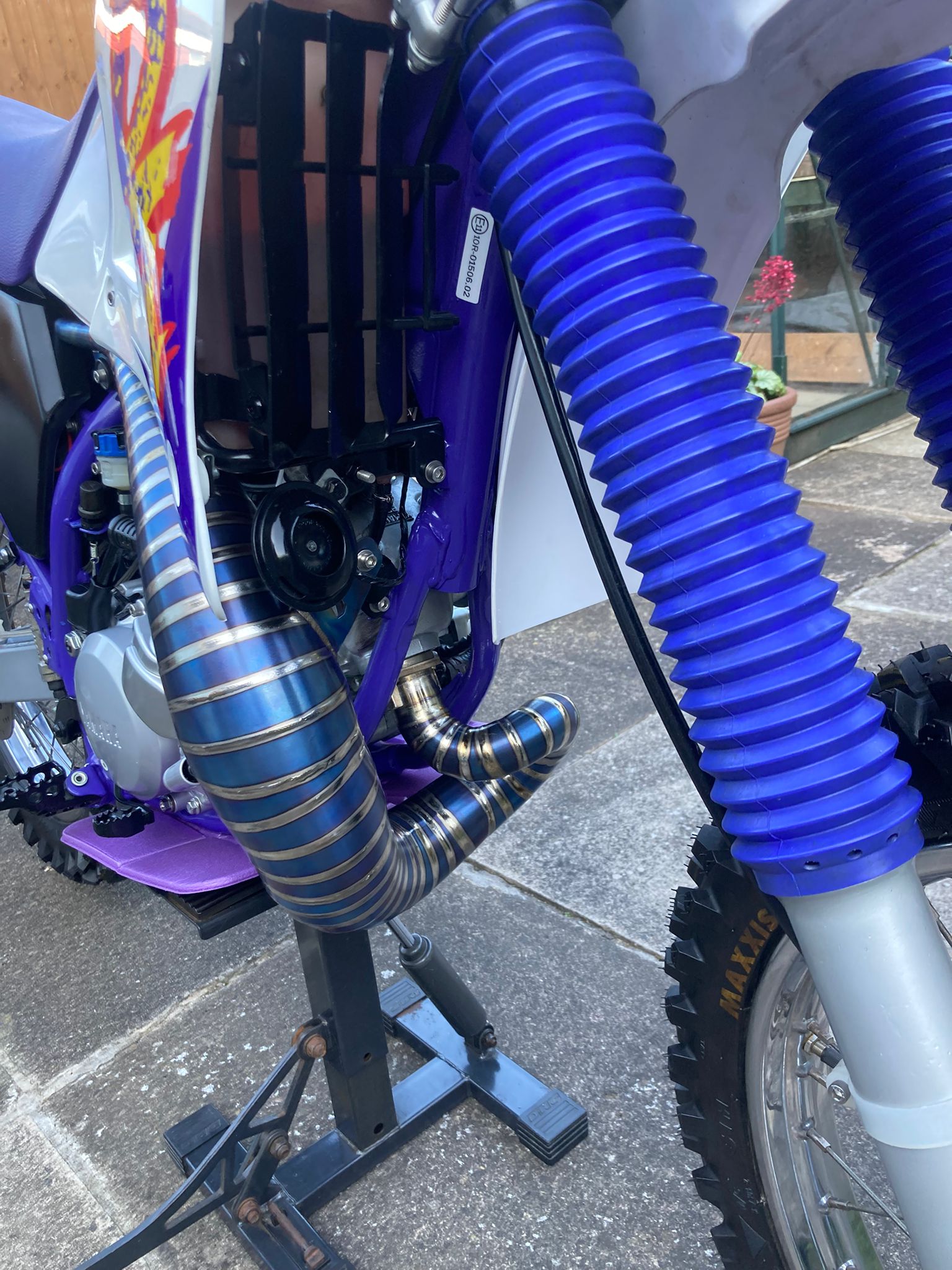 Close-up of a dirt bike with blue suspension forks on a concrete surface.