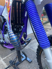 Close-up of a dirt bike with blue suspension forks on a concrete surface.